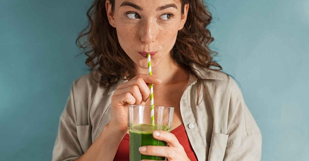 Una mujer toma un jugo verde. 